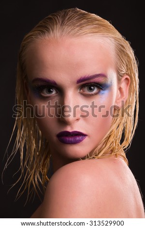 Model with makeup in unusual dress. Design image model. Stylish clothing and accessories. Professional makeup art. Model on a dark background.