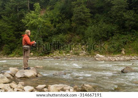 Fishing. Fishing in the highlands. Fisherman on the shore of a mountain, fast river. Trout fishing on the river. Active holiday in the mountains.
