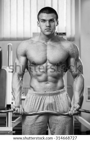Athlete with the stamp in the gym. Bench dumbbells and barbells. Work on tell muscles. Athlete train muscles of the hands and chest.