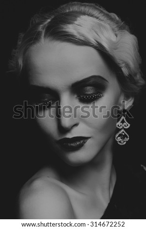 Beautiful blonde in a stylish image of a dark background. Elegant accessories and beautiful dress. Romantic and mysterious figure model.