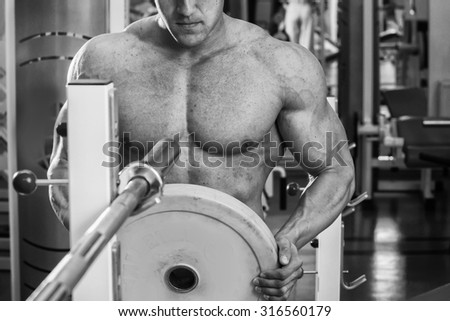 Muscular man in the gym. Work on the arm muscles. Training on a simulator. Exhausting work on his body.