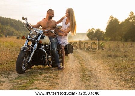 Young couple on a beautiful motorcycle in the field. Love and sincere feelings. Photo for motorcycle and social magazines and websites.