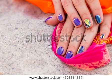 Beautiful hands with a professional manicure on the sand. Bright and beautiful manicure. Macro shooting hand. Photo for fashion magazines, websites and backgrounds.