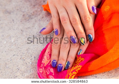 Beautiful hands with a professional manicure on the sand. Bright and beautiful manicure. Macro shooting hand. Photo for fashion magazines, websites and backgrounds.