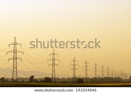 Transmission line at sunset with clear orange sky and no end pylons