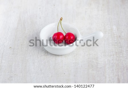 Two red sweet cherry in the white gravy boat