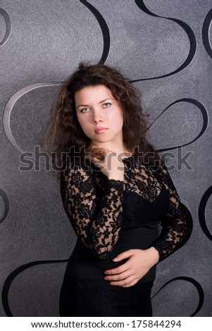 portrait of a young woman in a strict black lace dress on a gray background