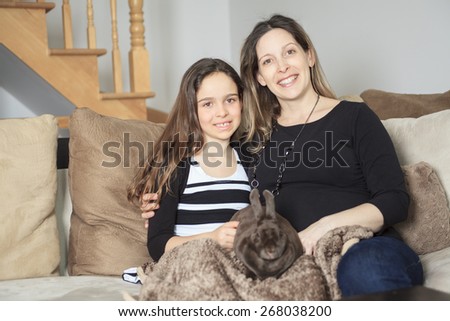 Young girl and mother with his pet rabbit at home.