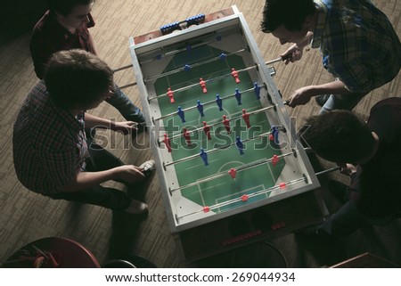 Some friends play soccer table in a bar.
