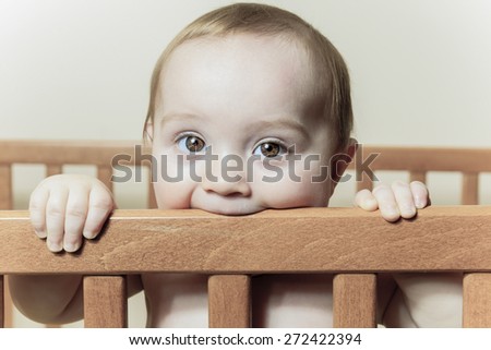 A Funny little baby with beautiful standing in a round white crib