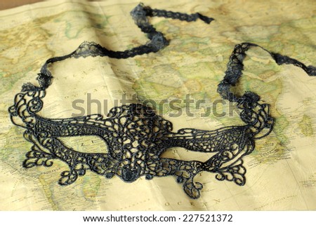 Black lace mask on a world map in a vintage decorate