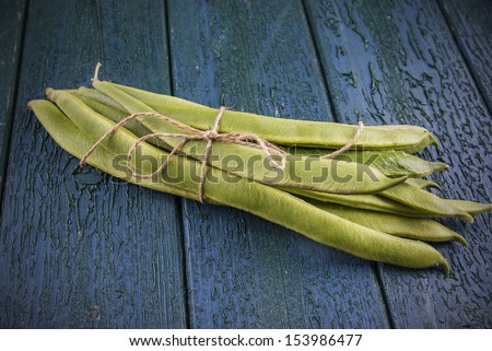 Runner beans ties in a bunch on a wooden tongue & groove board