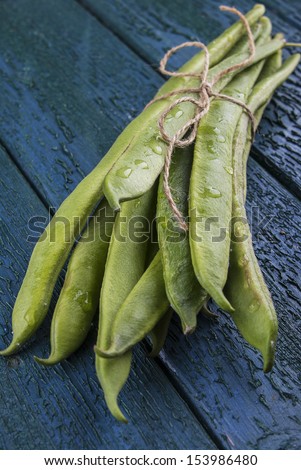 Runner beans ties in a bunch on a wooden tongue & groove board