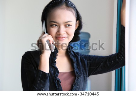 career woman smiling and calling near by window