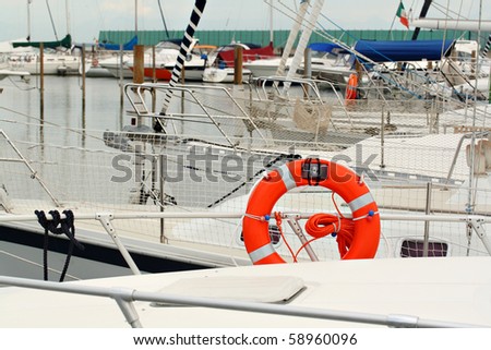Orange life buoy on white yacht berthed at marina