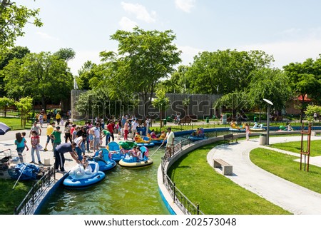 BUCHAREST, ROMANIA - JUNE 08, 2014: Children On Boat Ride In Youths Public Amusement Park (Tineretului Park) On Summer Day. Created in 1965 is one of the largest fun parks in south Bucharest.