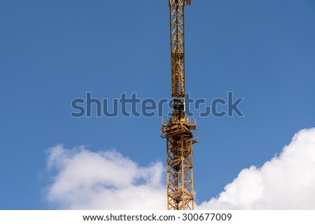 Industrial Construction Crane Against Blue Sky With Clouds