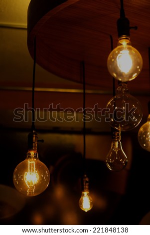 glowing and broken round bulb tungsten lamps on ancient chandelier, heated filament light, incandescent illumination on dark background