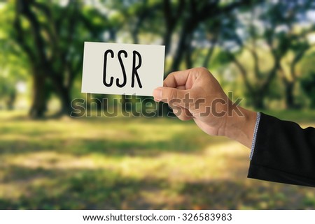 Hand holding a paper card with Corporate social responsibility (CSR) concept on abstract nature background