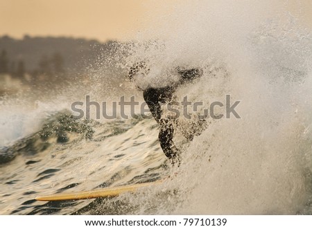 surfer balances on board breaking huge wave through splay foam pacific ocean water