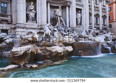 Italy ROme famous fountain di Trevi close up view from left side statues of gods and blurred water streams nobody around facade of richly decorated palace renaissance ancient centuries