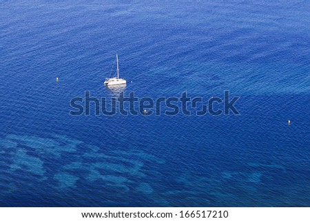 aerial view on lonely yacht anchored in the middle of shallow bay with transparent clean ocean water on sunny day