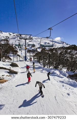 elevated view on active sport people in Perisher valley of Snow Mountains, AUstralia. Snowboarders and skiers are sloping down the hills underneath the chair lift