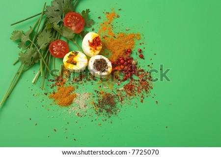 pieces of cheese with fresh vegetables and spices on green background