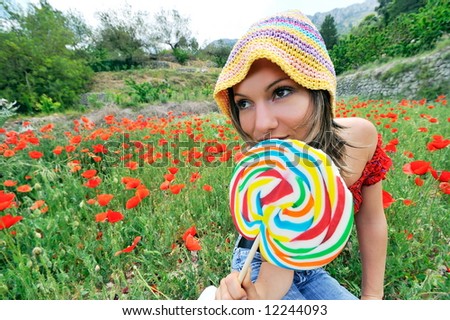 funny girl with colorful lollipop on a field with poppies