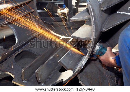 worker grinding a metal piece and sparks spreading