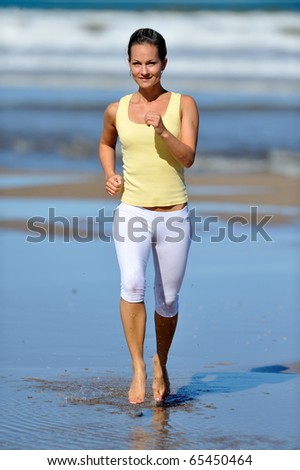 young woman jogging on the beach in summer