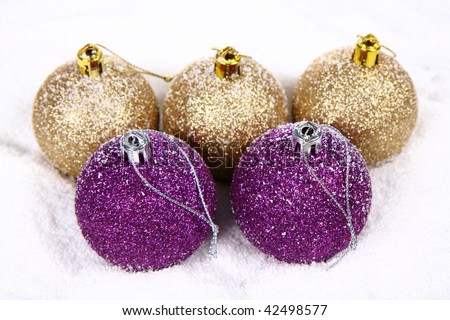 Purple and gold glittery christmas balls on white snow