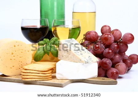 Various types of cheese (swiss, yellow, brie, blue cheese) with red and white wine, red grapes and crackers on white background in close up