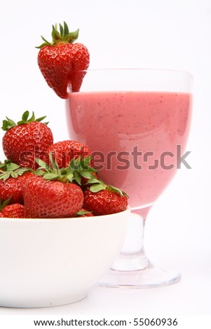 Strawberries in a bowl and a strawberry shake in a glass decorated with a strawberry on white background