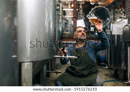 brewer examining taste and color of the beer in his craft beer brewery ストックフォト © 