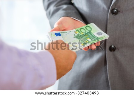 Close up of male hands offering and accepting money.