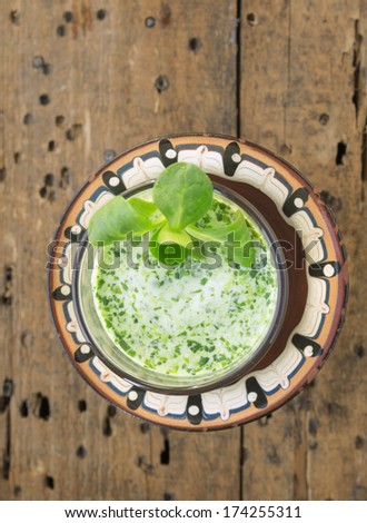 Field green salad smoothie in glass and brown bowl on old wooden table