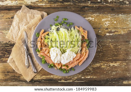 Poached eggs with green salad and salmon with knife and fork, copy space
