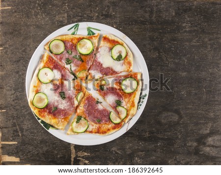 pizza with salami, zucchini and mozzarella on old table