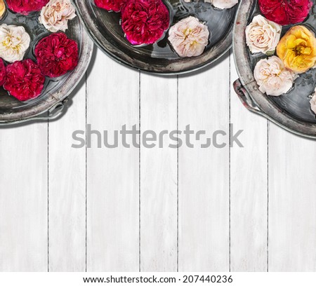 three buckets of water and roses on white wooden background