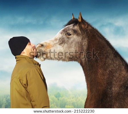 Horse kissing man in jacket and hat