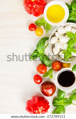 Mozzarella tomatoes salad ingredients on white wooden background, top view, vertical frame