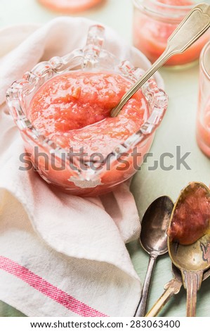 Cup of Rhubarb jam with vintage spoons and kitchen towel, close up