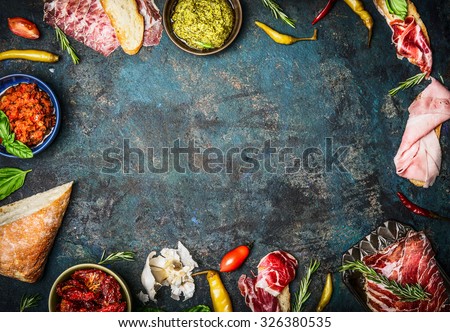 Ingredients for italian snack, bruschetta, crostini or sandwich bar with italian ham, sausage  and antipasto on rustic wooden background, top view, frame