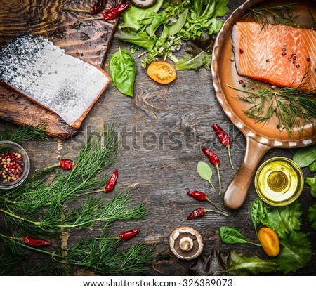 Fresh salmon fillet with ingredients for tasty cooking on rustic wooden background, top view, frame. Healthy food concept.