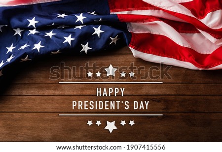  United States National Holidays. American or USA Flag with "HAPPY PRESIDENT'S DAY" text on wooden ement background, President Day concept