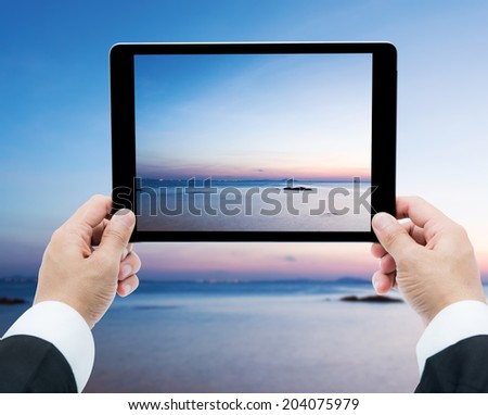 Businessman hands tablet taking pictures Beautiful Landscape  Sea and Sky of Sunset at Thailand