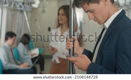 Close up businessman standing on the seat using modern smartphone to internet checking news on electric train, Passenger young man commuting texting on mobile phone by railway transport 商業照片 © 