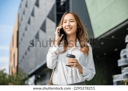 Asian young businesswoman walking outdoors talking on cell smart mobile phone and holding coffee cup takeaway, lifestyle business woman hold paper cup and calling smartphone outside office Сток-фото © 