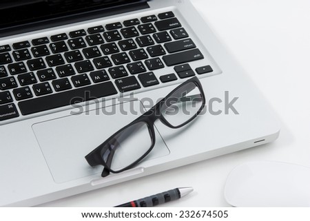 Blank business laptop, mouse, pen and glasses on white table
